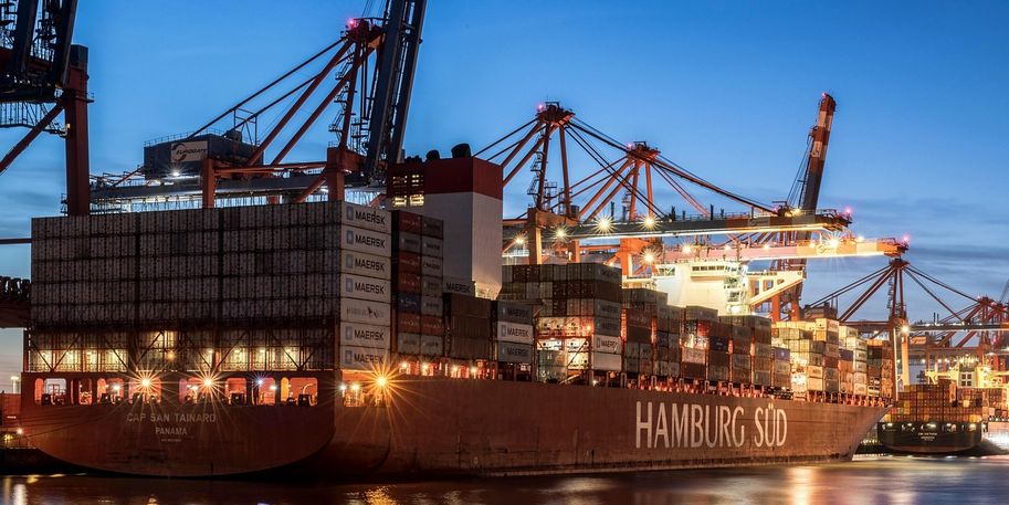 [Translate to English:] Containerschiff in der Dämmerung am Hamburger Hafen