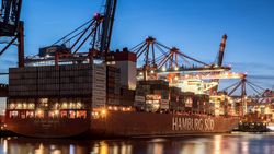 [Translate to English:] Containerschiff in der Dämmerung am Hamburger Hafen