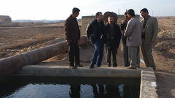 Sechs Personen stehen an einem Becken zur Abwasserbehandlung im Iran