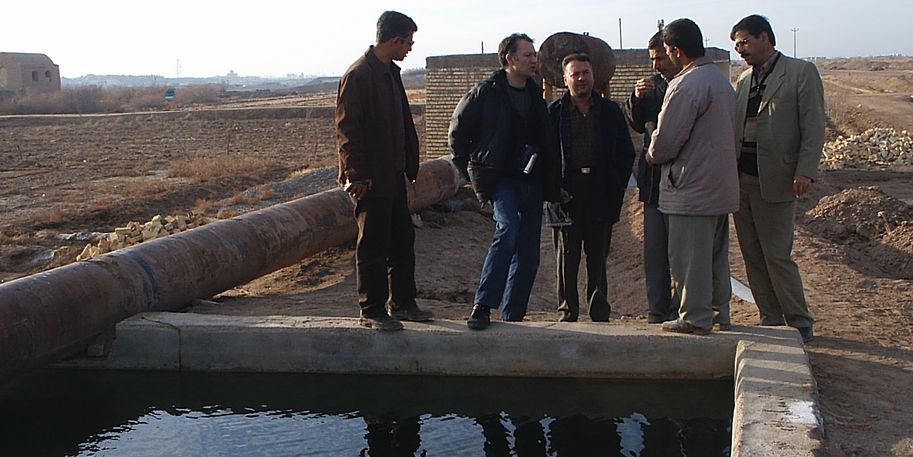 Sechs Personen stehen an einem Becken zur Abwasserbehandlung im Iran